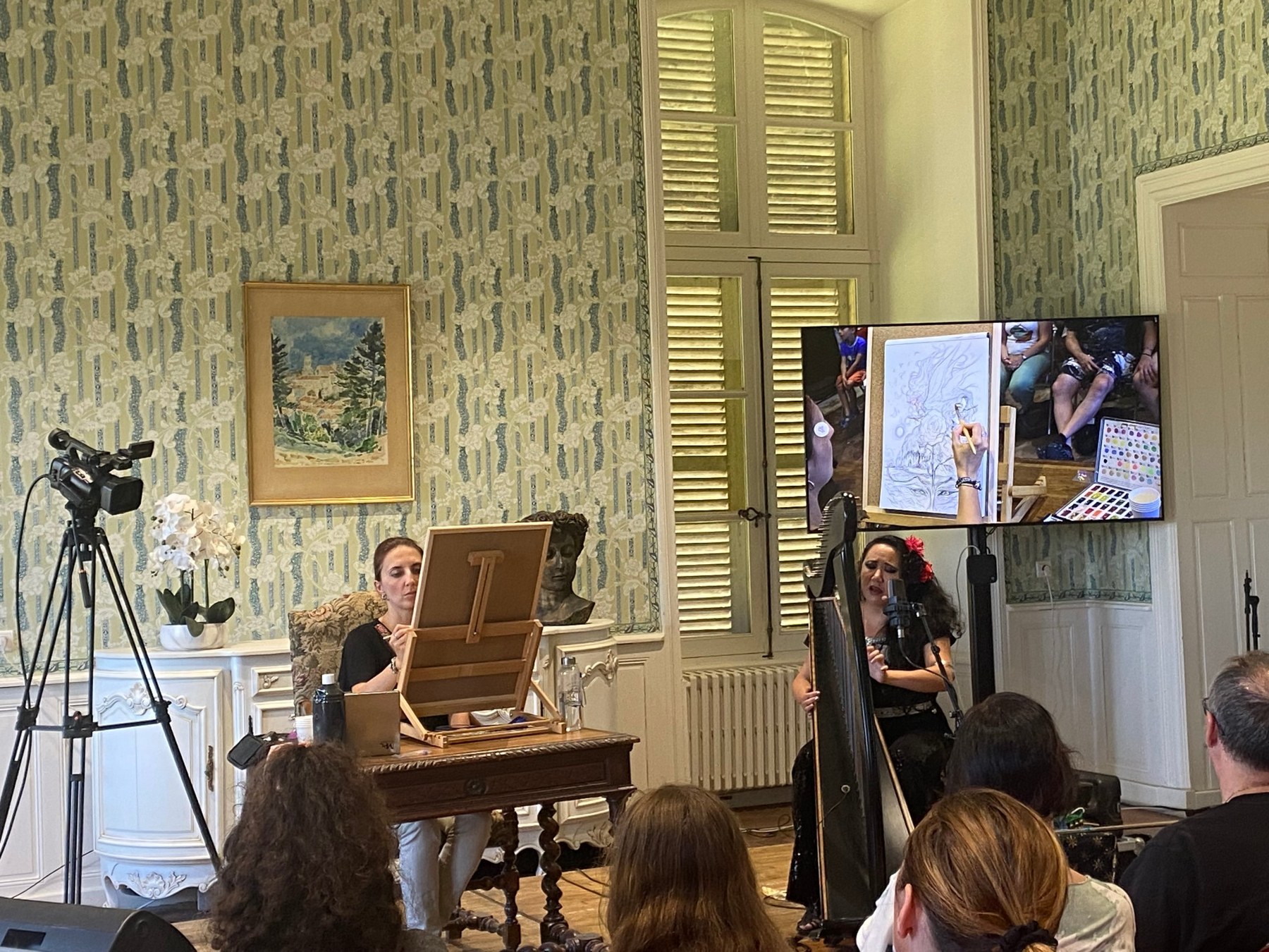 Nora Moretti dessine en direct, son dessin projeté sur grand écran, pendant qu’Ameylia Saad Wu joue de la harpe et chante
